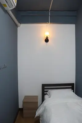 a bedroom with a bed and a light on the wall at The Moment Hostel in Bangkok