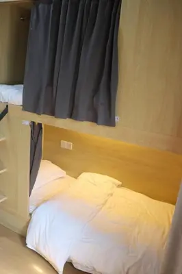 a bed in a dorm room with a window at The Moment Hostel in Bangkok