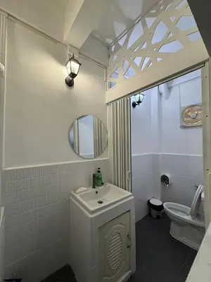 a bathroom with a sink and a toilet and a mirror at The Moment Hostel in Bangkok