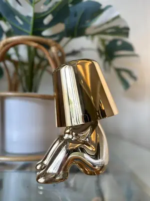 a brass sink faucet in front of a plant at BangrakHomey - Cozy private Apartment in State tower bangkok in Bangkok