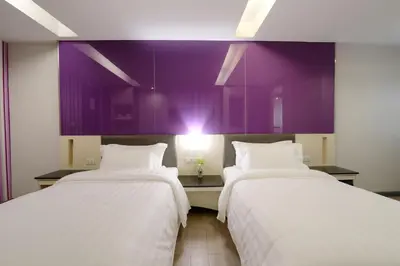 two beds in a room with purple walls at Klassique Sukhumvit Hotel in Bangkok