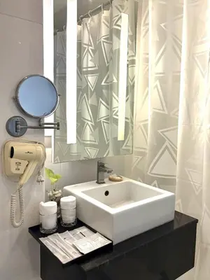 a bathroom with a white sink and a mirror at Klassique Sukhumvit Hotel in Bangkok