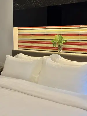 a bed with white pillows and a vase with a plant at Klassique Sukhumvit Hotel in Bangkok