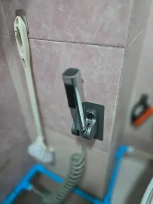 a phone on a bathroom wall with a hose at 104 Peaceful and Cosy apartment near BTS with free WiFi in Bangkok