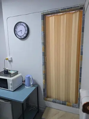 a kitchen with a table with a microwave and a clock at 104 Peaceful and Cosy apartment near BTS with free WiFi in Bangkok