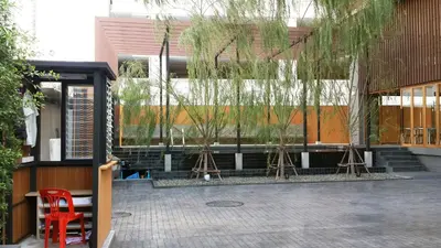 a red chair in front of a building with trees at Sereine Sukhumvit 39 in Bangkok