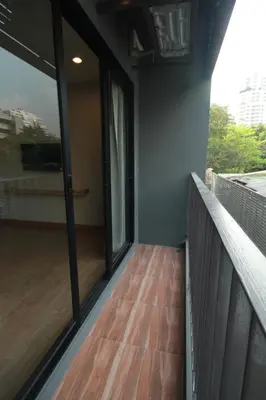 a balcony with glass doors and a wooden floor at Sereine Sukhumvit 39 in Bangkok