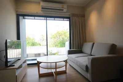 a living room with a couch and a table and a window at Sereine Sukhumvit 39 in Bangkok