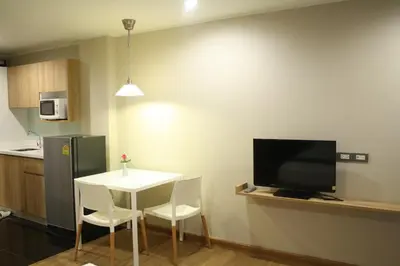a small kitchen with a white table and a television at Sereine Sukhumvit 39 in Bangkok