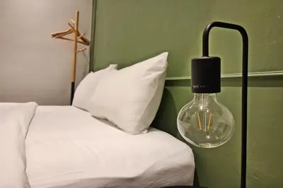 a glass lamp next to a bed with white sheets at Shade House Bangkok Oldtown in Bangkok