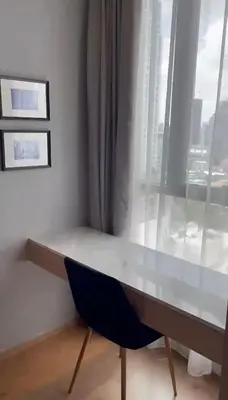 a desk with a blue chair sitting next to a window at Condo Luxe Siam Pool 360 Near BTS Shopping in Bangkok