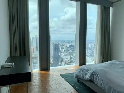 a bedroom with large windows with a bed and a desk at Ritz Carlton Residences in Bangkok
