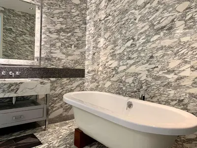 a white bath tub in a bathroom with marble walls at Ritz Carlton Residences in Bangkok