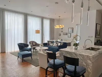 a living room with a kitchen and a living room with blue chairs at Ritz Carlton Residences in Bangkok