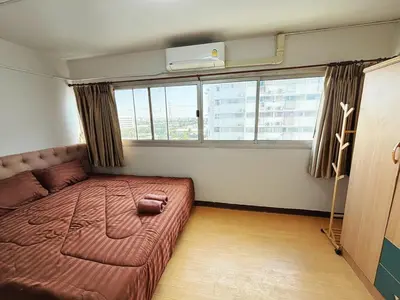 a bedroom with a large bed in a room with windows at Impact - Don Mueng Condo C5 in Thung Si Kan