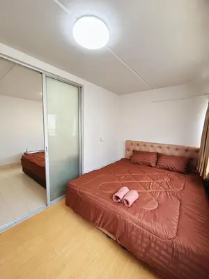 a bedroom with a bed with a pink slippers on it at Impact - Don Mueng Condo C5 in Thung Si Kan