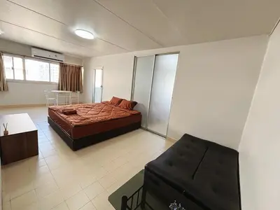 a bedroom with a bed and a chair in it at Impact - Don Mueng Condo C5 in Thung Si Kan