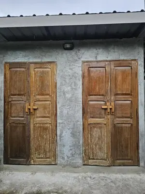 two wooden doors on the side of a building at บ้านรังนก The Bird Nest Homestay & Coffeeshop in Samut Prakan