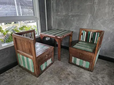 a couple of chairs and a table and a chair at บ้านรังนก The Bird Nest Homestay & Coffeeshop in Samut Prakan
