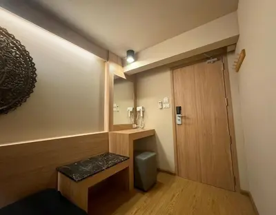 a small bathroom with a toilet and a wooden door at Mind Day Hostel Khaosan in Bangkok