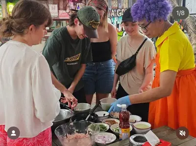 a group of people standing around a table preparing food at Here Hostel Bangkok in Bangkok