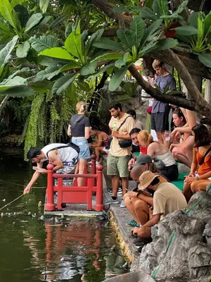 a group of people sitting around a red bench in the water at Here Hostel Bangkok in Bangkok