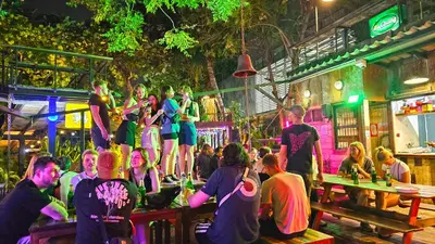 a group of people standing on a stage in a bar at Here Hostel Bangkok in Bangkok