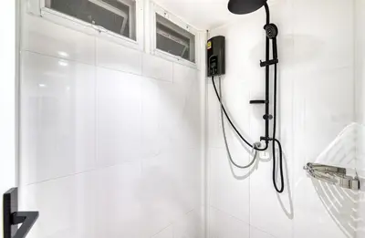 a shower in a white bathroom with a window at AB House in Bangkok