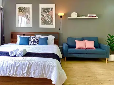 a bedroom with a bed and a blue couch at Impact Arena Condo 10fl by GoodRoom24 in Ban Song Hong