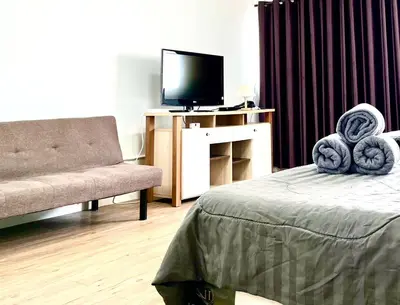 a living room with a bed and a television at Impact Arena Condo Twin Beds by Goodroom24 in Ban Song Hong