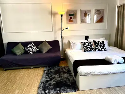 a living room with a bed and a couch at Impact Arena C8 Condo by GoodRoom24 in Thung Si Kan