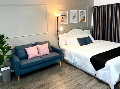 a bedroom with a bed and a blue couch at Impact Arena Condo C3 Grey by GoodRoom24 in Ban Bang Phang
