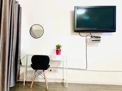 a desk with a television on a wall with a chair at Impact Arena Condo C3 Grey by GoodRoom24 in Ban Bang Phang