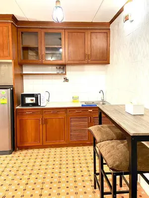 a kitchen with wooden cabinets and a table with chairs at Impact Arena Condo The Classic by GoodRoom24 in Ban Song Hong