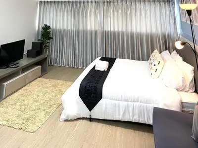 a bedroom with a white bed and a flat screen tv at Impact Arena Condo TwoTone By GoodRoom24 in Ban Song Hong
