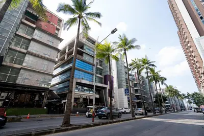 a street with palm trees and a tall building at Spacious 3BR near Impact, Don Mueang Airport & Pink Line MRT in Nonthaburi