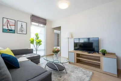 a living room with a couch and a flat screen tv at Spacious 3BR near Impact, Don Mueang Airport & Pink Line MRT in Nonthaburi