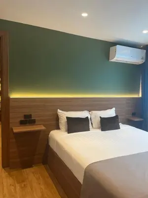 a bedroom with two beds and a green wall at Executive Apartment Thonglor in Bangkok