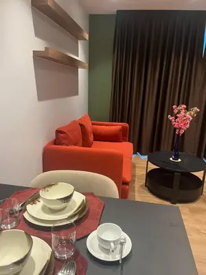 a living room with a red couch and a table with dishes at Executive Apartment Thonglor in Bangkok