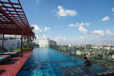 a man sitting in a swimming pool on top of a building at Sukhumvit Bts ideomix1 in Amphoe Phra Khanong