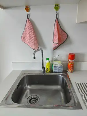 a kitchen sink with two hanging hooks on the wall at Cozy Apartment Night Market and Shopping Mall at MRT Purple Line in Nonthaburi