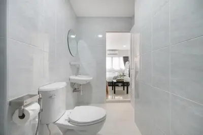 a white bathroom with a toilet and a sink at Arun Sa wad - Chinatown in Bangkok