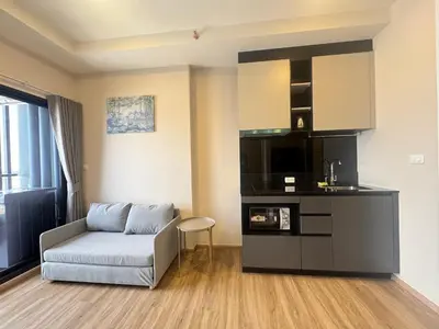 a living room with a couch and a kitchen at Neon Cloud Bangkok in Bangkok