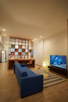 a living room with a blue couch and a flat screen tv at The companions house in Sathani Bang Su