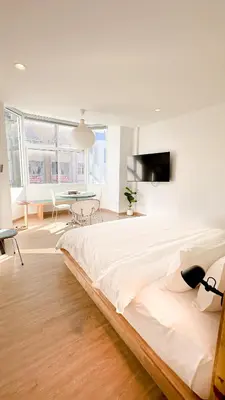 a white bedroom with a large bed and a table at The companions house in Sathani Bang Su