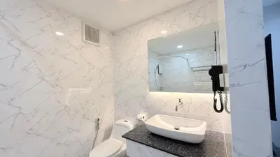 a white bathroom with a sink and a mirror at Issara House Bangkok in Bangkok