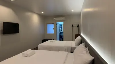 a hotel room with two beds and a television at Issara House Bangkok in Bangkok