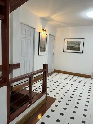 a hallway with a white door and a black and white tile floor at Silpasala StayZ in Sathani Ban Hua Mak