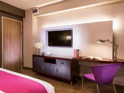 a bedroom with a desk with a tv and purple chairs at Ratchada Point Hotel in Bangkok