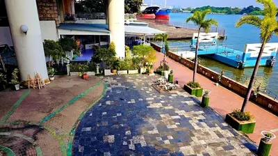 a stone walkway next to a marina with palm trees at River View Bangkok in Bangkok